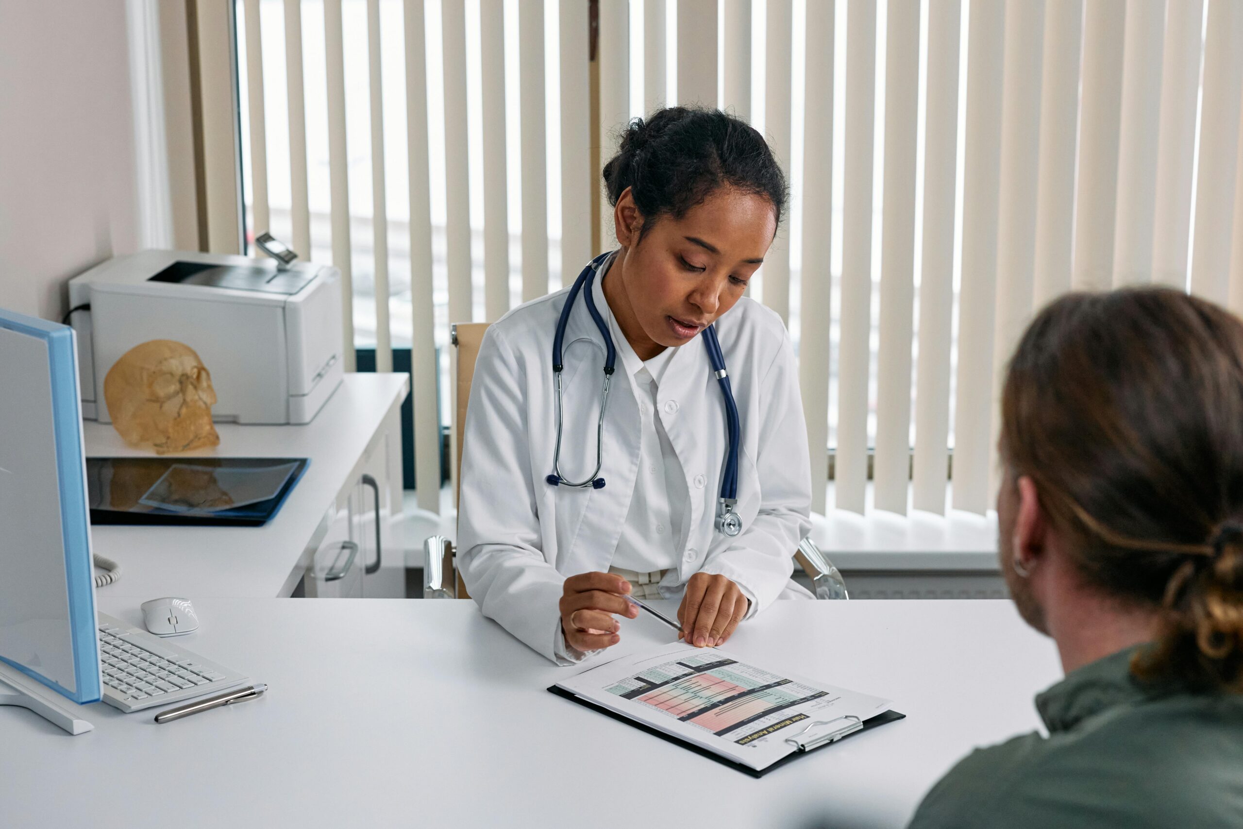 A doctor consulting with a patient in an office, discussing a medical chart.